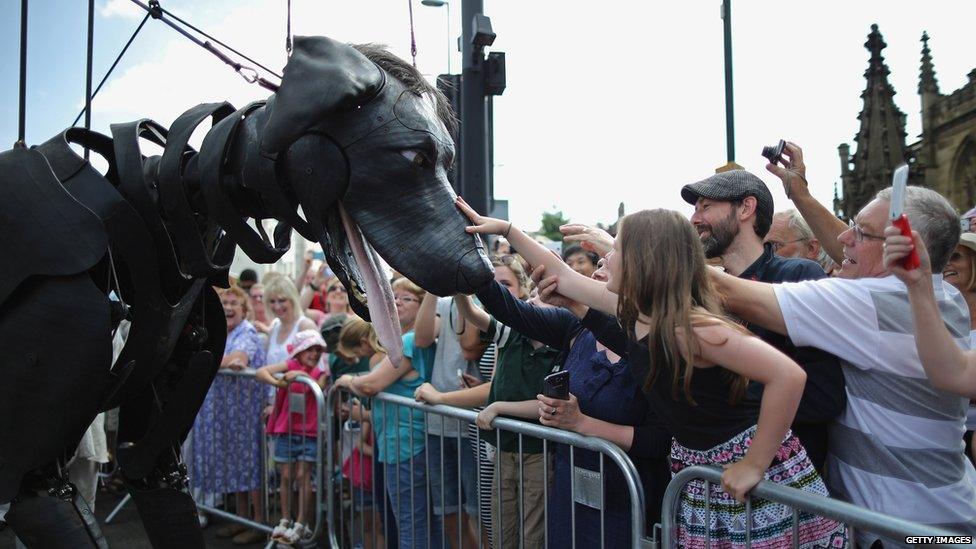 Spectators pet a giant puppet dog.