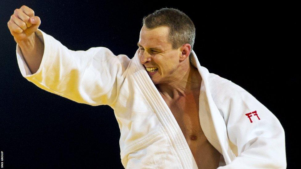 Scottish flag bearer Euan Burton celebrates victory in the -100kg category