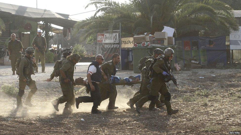 Israeli soldiers carry their comrade on a stretcher after he was wounded in a Palestinian mortar strike, as they evacuate him from the scene outside the central Gaza Strip July 28, 2014.