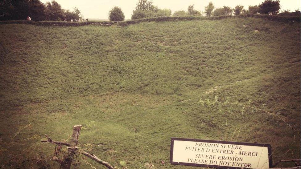 A large crater in the ground, now covered in grass so looks like a hill