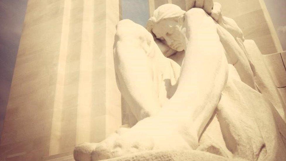 A large white stone statue sits with its eyes closed