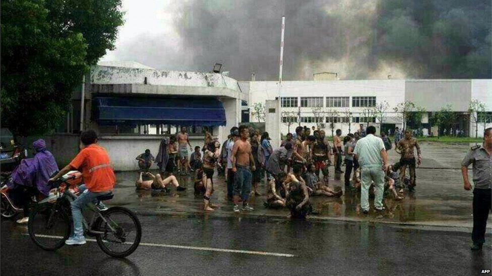 Victims gather outside the gate of a factory after an explosion in Kunshan, 2 Aug