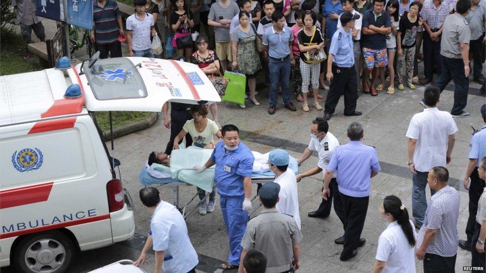 Medical personnel transport a victim (C) at a hospital after an explosion at a factory in Kunshan, 2 Aug