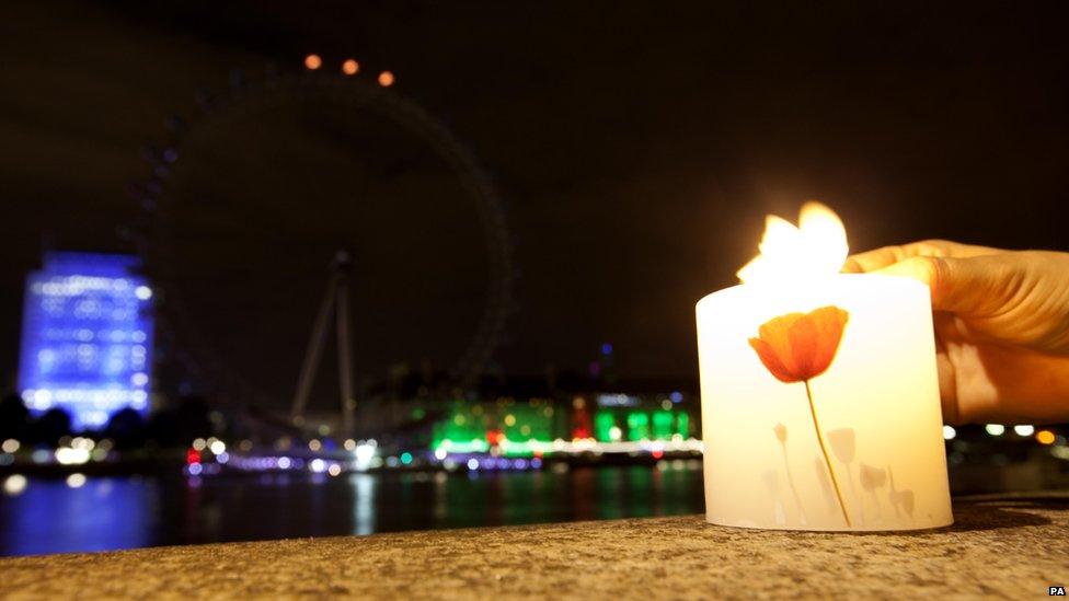 A candle is lit as the London Eye on London's South Bank has its lights switched off