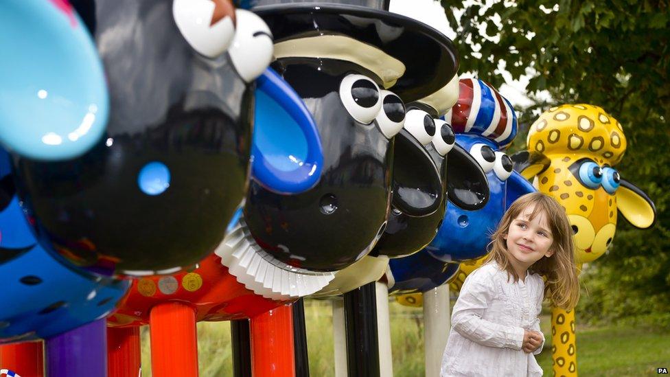 Girl looking at Shaun the Sheep sculptures