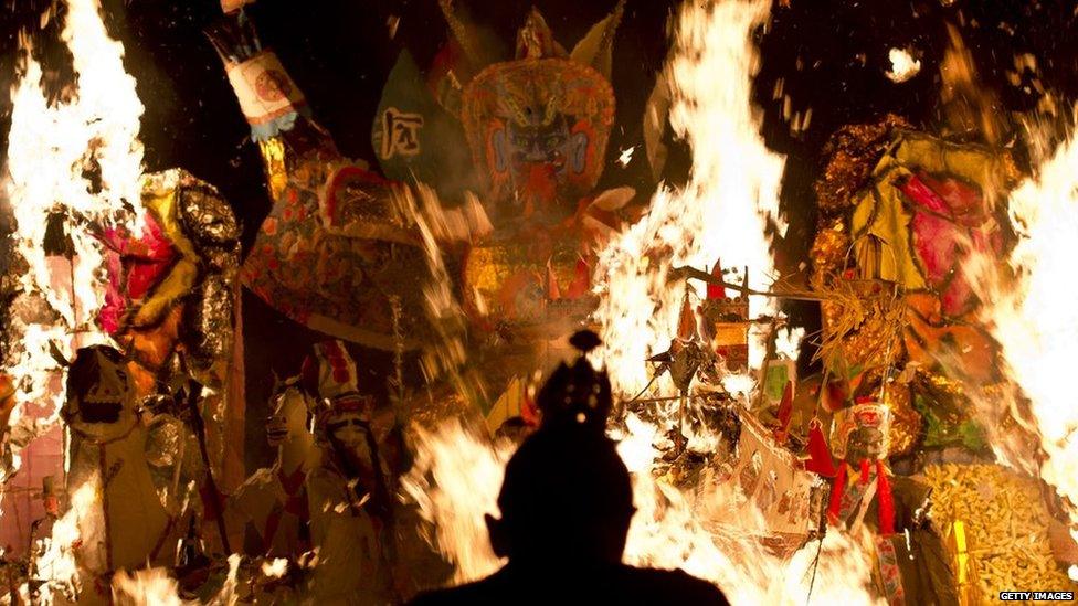 An Ethnic Chinese priest stands in front of statue made of paper of Chinese deity "Da Shi Ye" or Guardian God of Ghosts set of fire by devotees during the Hungry Ghost festival in Kuala Lumpur, late on 10 August, 2014