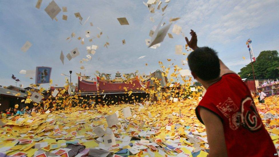 An ethnic-Chinese Indonesian man throws "hell money" prepared as offerings for his ancestors" souls into the air during the "hungry ghost" festival in Medan, North Sumatra, Indonesia, on Sunday, 10 August 2014