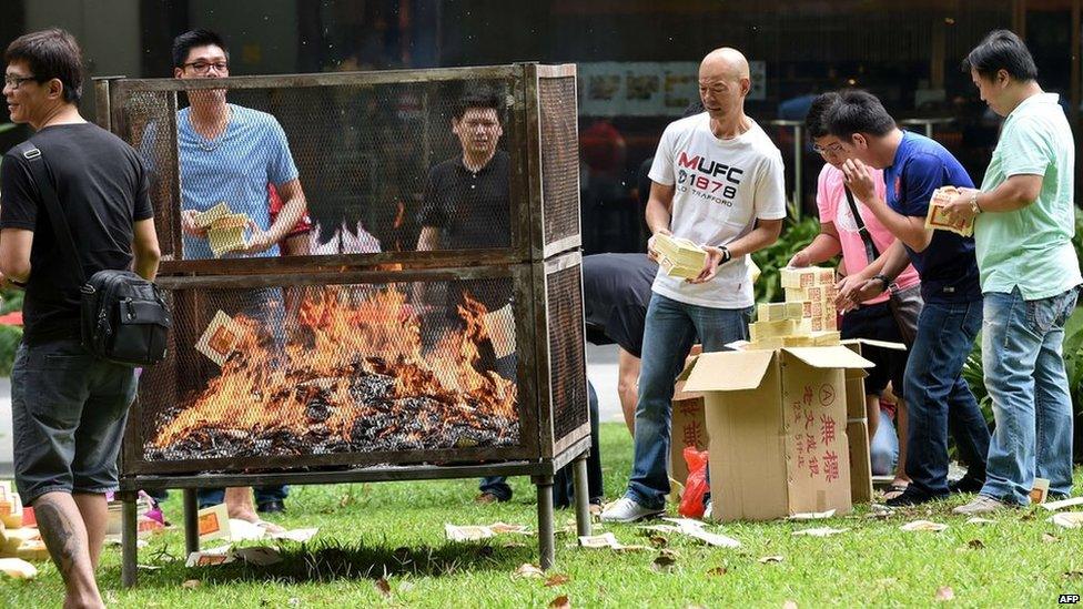 Employees from a nearby office building burn offerings to mark the Hungry Ghost Festival in Singapore on 8 August, 2014