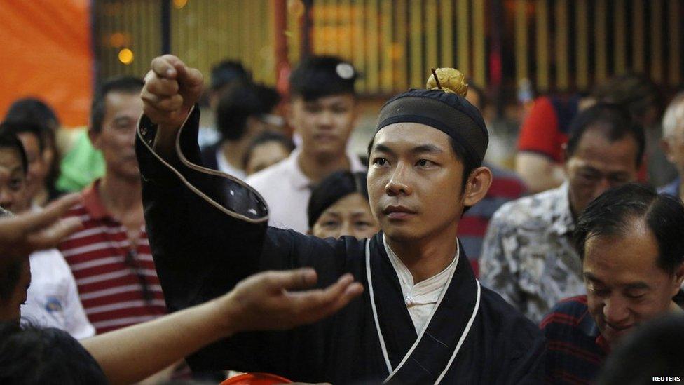 A monk throws coins to worshippers for good luck during preparations for the Hungry Ghost festival in Kuala Lumpur on 3 August, 2014