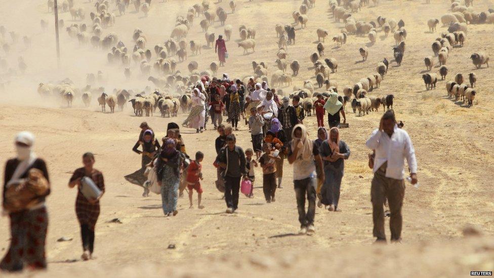 Displaced people from the minority Yazidi sect, fleeing violence from forces loyal to the Islamic State in Sinjar town, walk towards the Syrian border, on the outskirts of Sinjar mountain, near the Syrian border town of Elierbeh of Al-Hasakah Governorate.