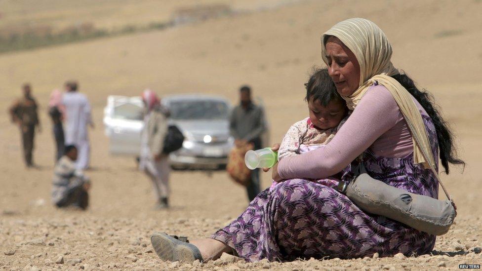 A displaced woman and child from the minority Yazidi sect, fleeing violence from forces loyal to the Islamic State in Sinjar town, rest as they make their way towards the Syrian border, on the outskirts of Sinjar mountain, near the Syrian border town of Elierbeh of Al-Hasakah Governorate on 10 August 2014.