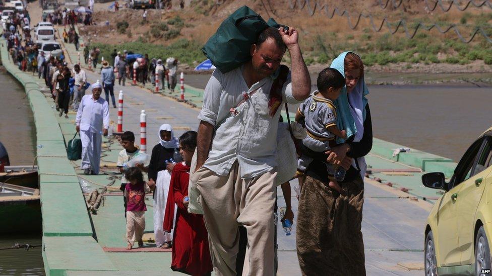 Displaced Iraqis from the Yazidi community cross the Iraqi-Syrian border along the Fishkhabur bridge over the Tigris River at the Fishkhabur crossing, in northern Iraq, on 11 August 2014.