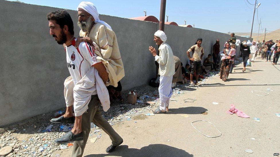 Displaced Iraqis from the Yazidi community cross the Syria-Iraq border at the Feeshkhabour bridge over Tigris River at Feeshkhabour border point, in northern Iraq, on 11 August 2014.