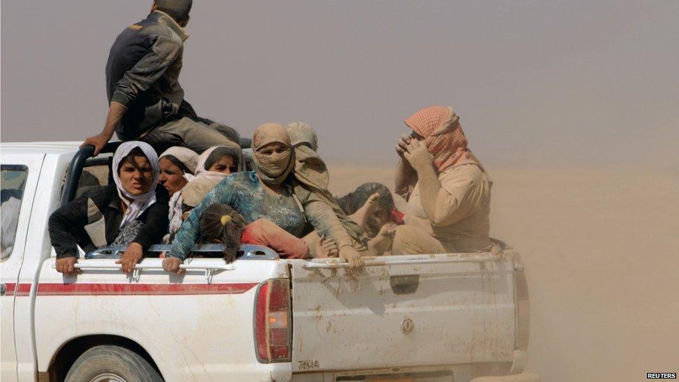 Displaced people from the minority Yazidi sect, fleeing violence from forces loyal to the Islamic State in Sinjar town, ride a truck as they make their way towards the Syrian border, on the outskirts of Sinjar mountain, near the Syrian border town of Elierbeh of Al-Hasakah Governorate on 10 August 2014.