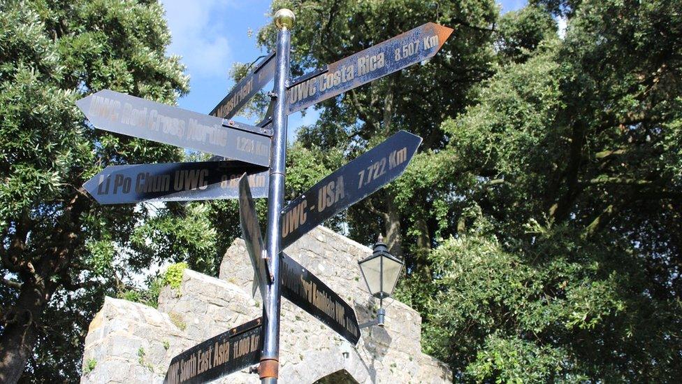 Arwydd sydd yn dangos lleoliadau a phellter colegau eraill Colegau Undebol y Byd. // A signpost showing the locations and distances of the other United World Colleges.