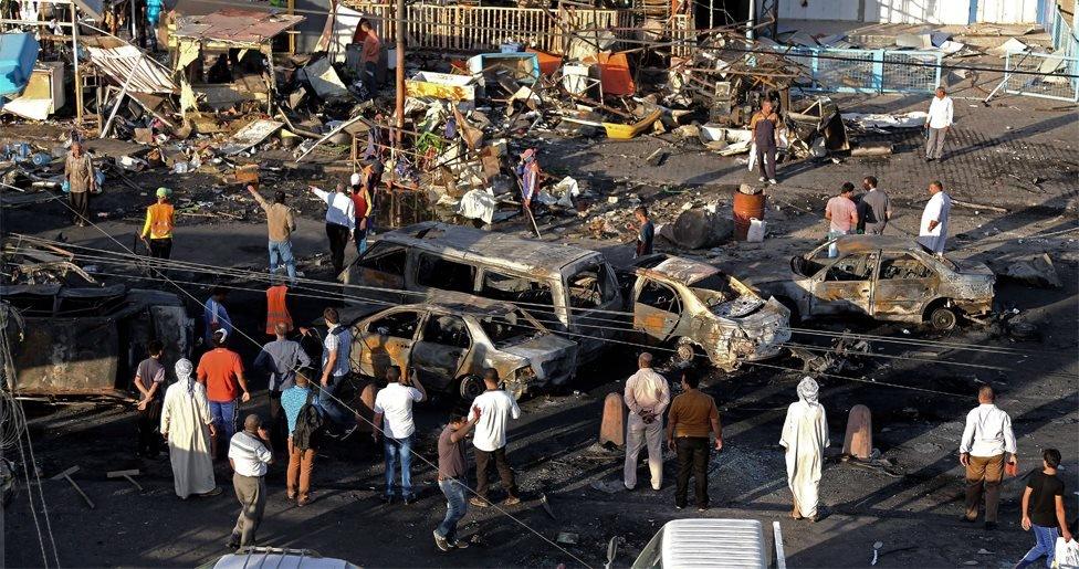 Iraqi civilians gather the morning after a string of car bombs tore through busy shopping streets in several neighborhoods in Baghdad, Iraq