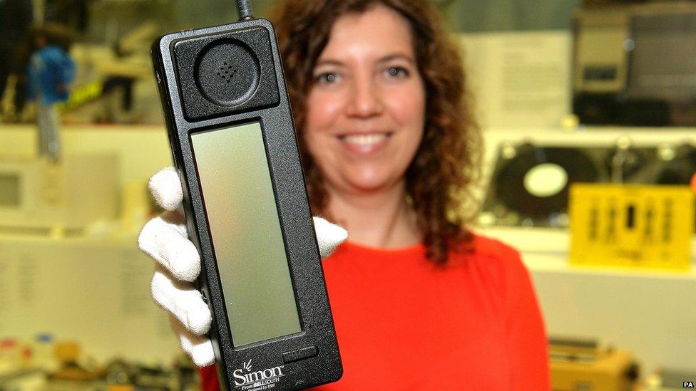 A museum employee holds up the IBM Simon, the first smartphone to go on sale 20 years ago