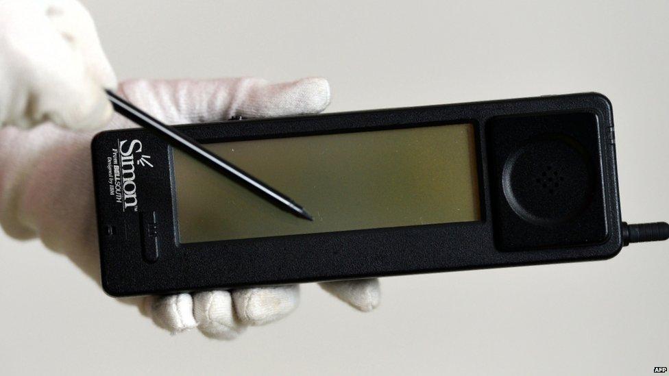 A museum employee holds up the IBM Simon, the first smartphone to go on sale 20 years ago