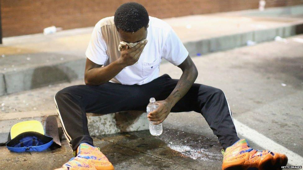A protester relieves his eyes after tear gas is thrown