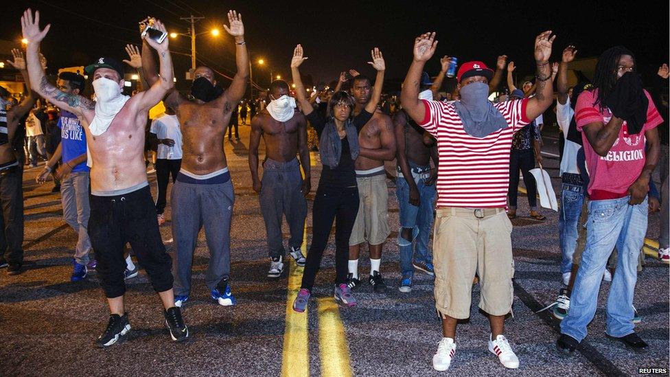 Demonstrators gesture with their hands up after protests in reaction to the shooting of Michael Brown turned violent near Ferguson, Missouri, 17 August 2014