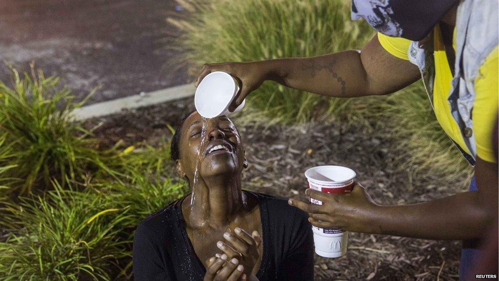 Protesters react to the effects of tear gas which was fired at demonstrators reacting to the shooting of Michael Brown in Ferguson, Missouri, 17 August 2014