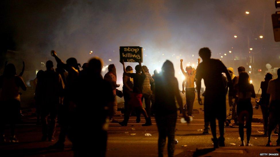 Demonstrators react as police fire tear gas at them as they protest the shooting death of Michael Brown in Ferguson, Missouri, 17 August 2014