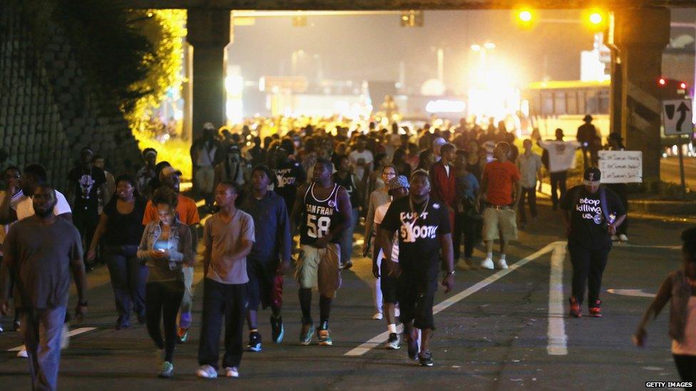 Demonstrators walk down the street as they protest the shooting death of Michael Brown in Ferguson, Missouri, 17 August 2014