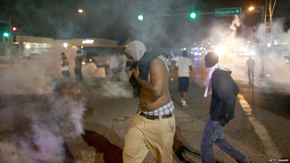 Demonstrators react as police fire tear gas at them while protesting the shooting death of Michael Brown in Ferguson, Missouri, 17 August 2014