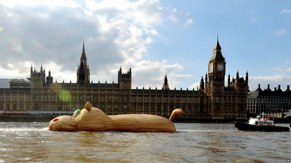 Giant hippo sculpture floats past Houses of Parliament.