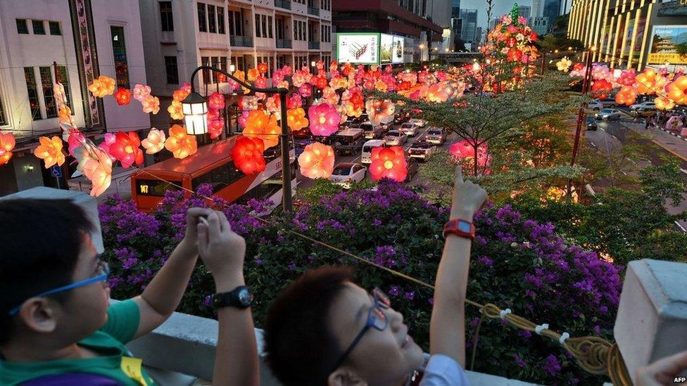 Children look at floral lanterns hang above a street during a media preview of the upcoming mid-autumn festival in Singapore on 31 August, 2014