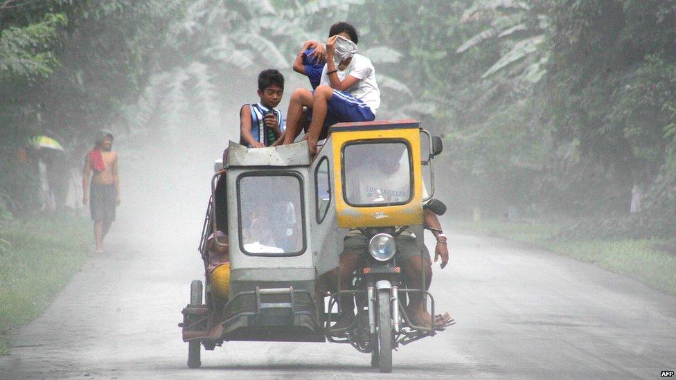 Children cover their faces to avoid inhaling ash after Mount Mayon in the Philippines shot a column of ash into the air on 28 December, 2009