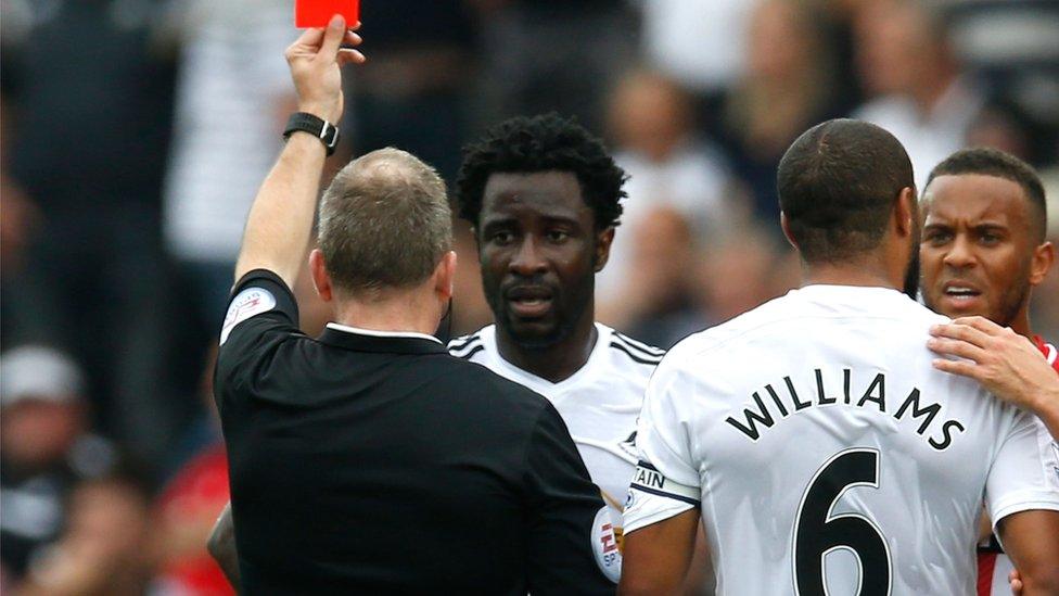 Swansea skipper Ashleigh Williams looks on as Wilfried Bony is shown the red card by referee Jonathan Moss