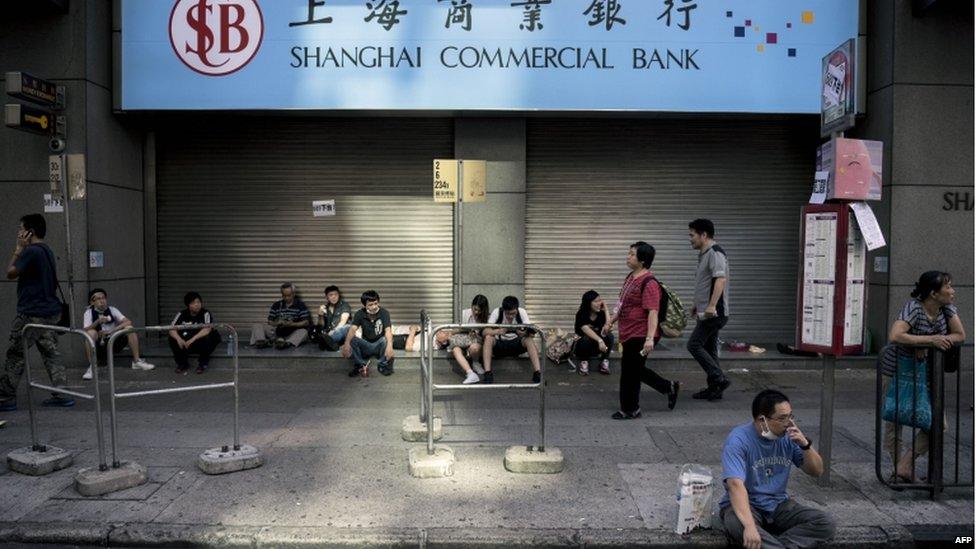 People gather next to a shuttered branch of the Shanghai Commercial Bank as a pro-democracy protest continues on Nathan Road, a major route through the heart of the Kowloon district of Hong Kong, on 29 September 2014.