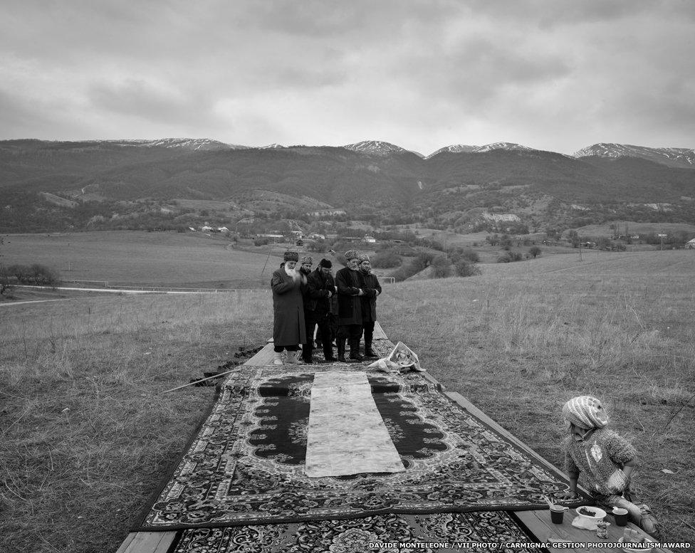 A group of elderly people praying in the mountains