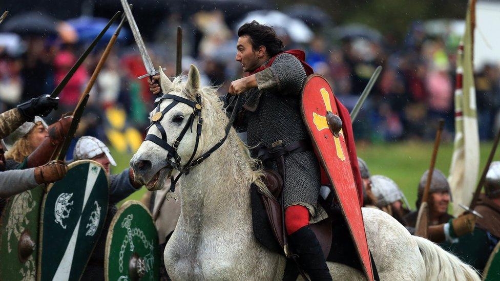 A re-enactor plays the Duke of Normandy (centre) attacking the Saxons on horseback