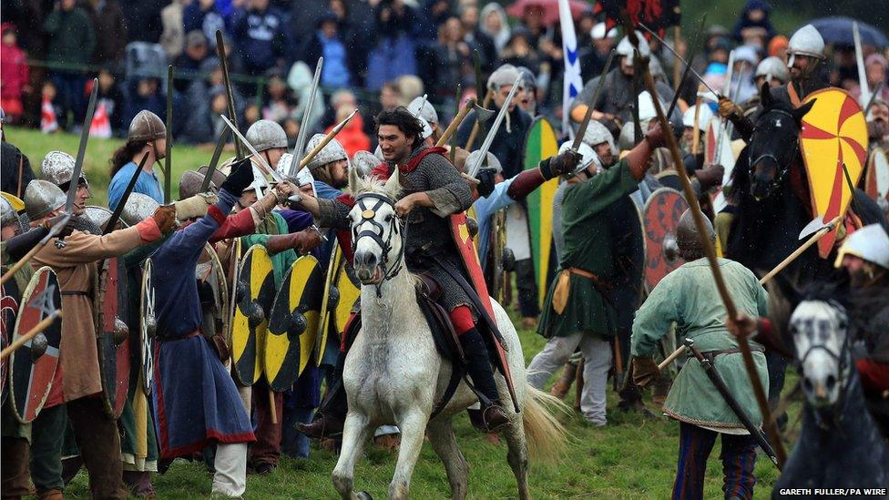 A re-enactor plays the Duke of Normandy (centre) attacking the Saxons on horseback