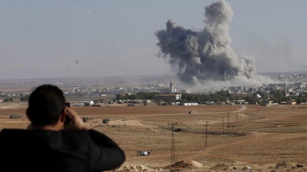 A man watches from a hill as smoke rises after an US-led coalition airstrike on Kobane, Syria, on the Turkish side of the border, near Suruc district, Sanliurfa, Turkey, 18 October 2014