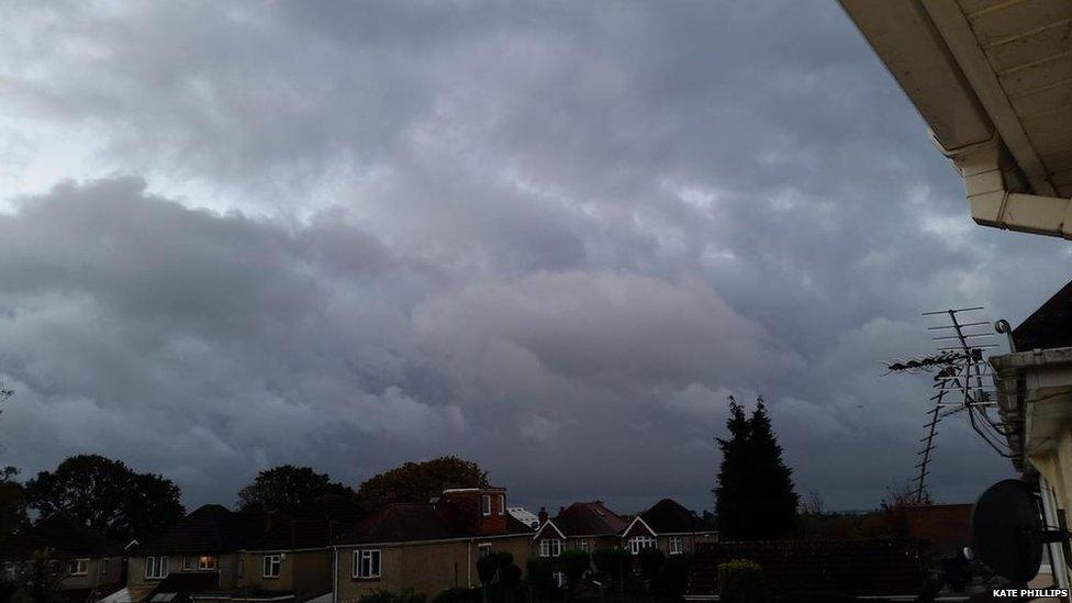 Dark grey clouds over rooftops.