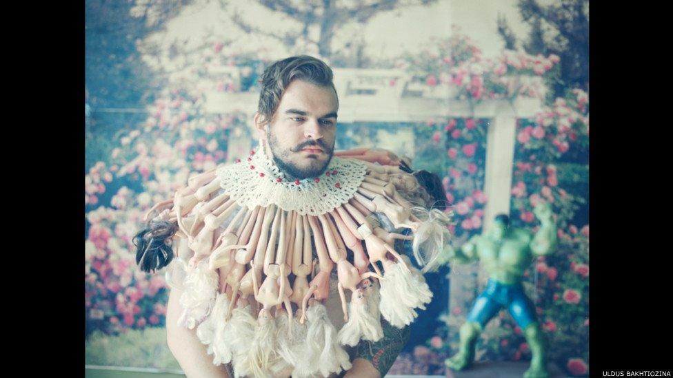 Man with neck ruff made from barbie dolls