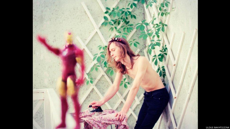 Man ironing with red statue at the back