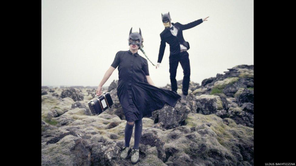 Woman and man with batman helmets on and a radio stereo