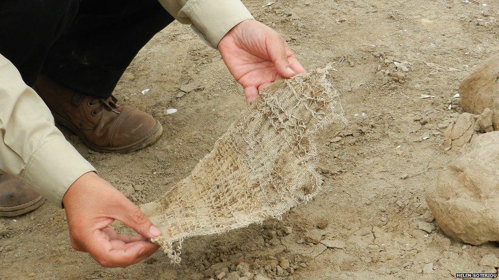 Mr Falcon holds up a piece of woven fabric at Huaca Malena