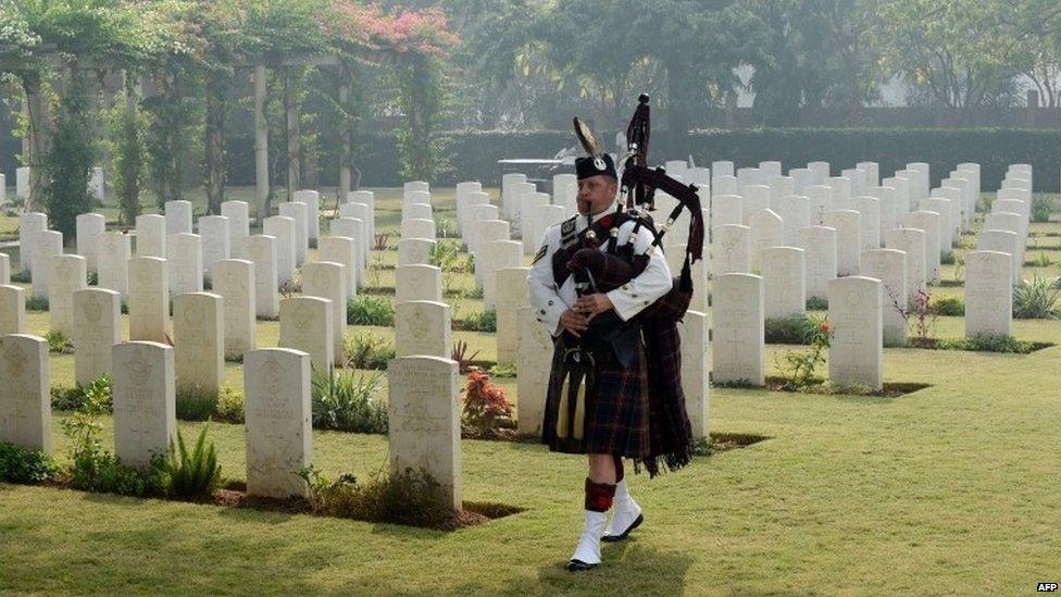 Bagpiper walks among graves at Delhi War Cemetery