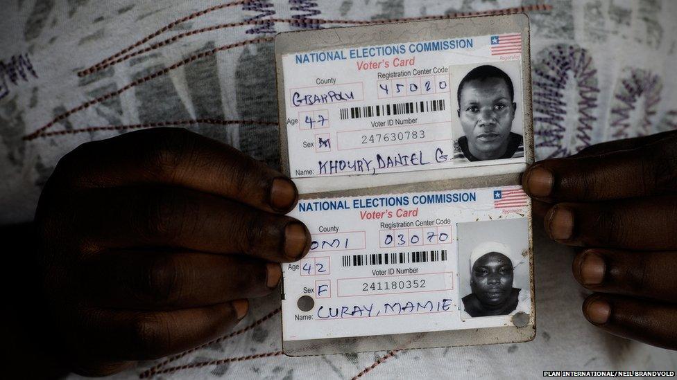 Fatu, 32, with parents’ ID cards, the only pictures they have of them