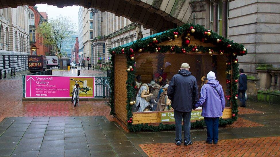 A couple looks at the nativity scene outside the council house