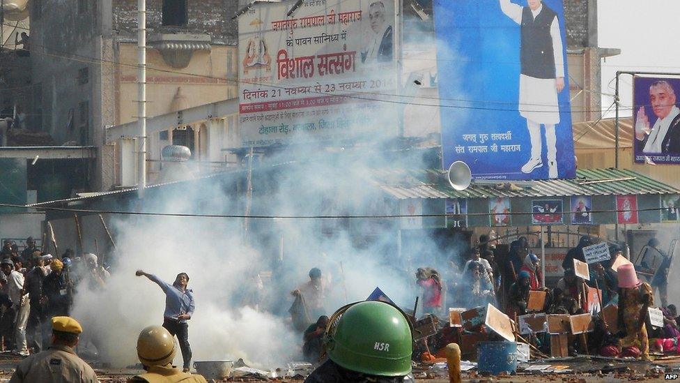 Indian security officials look on as an activist throws a stone in Hisar some 175kms north of New Delhi on November 18, 2014