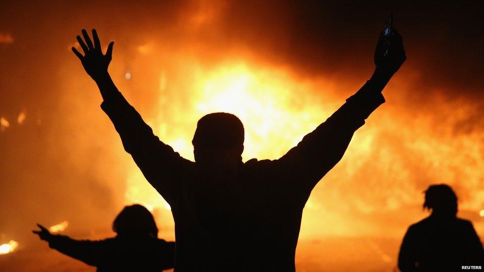 Demonstrators celebrate as a business burns after it was set on fire in Ferguson, Missouri (25 November 2014)