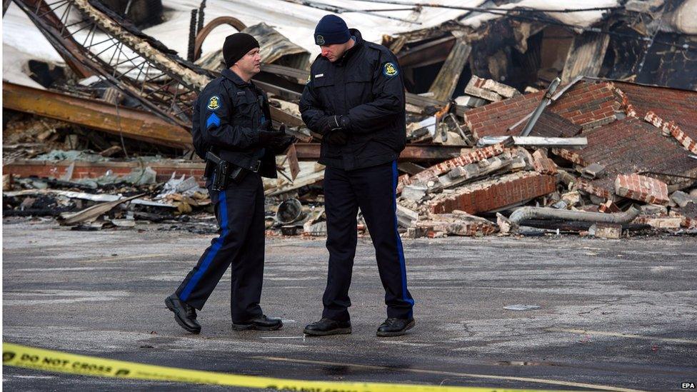 Policeman talk near one of the burnt businesses as West Florissant Avenue is closed for police investigation, in Ferguson, Missouri, USA, 25 November 2014