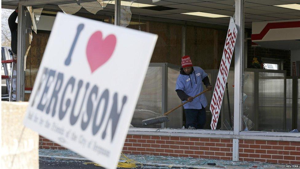 People clean up a business that was damaged in riots the previous night in Ferguson, Missouri November 25, 2014