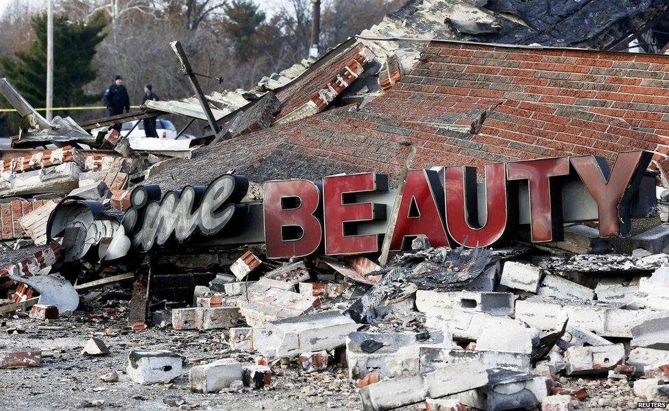 Police officers look over the site of a building that was burned in riots the previous night in Ferguson, Missouri November 25, 2014